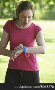 Female Runner In Park Checking Time Using Stopwatch