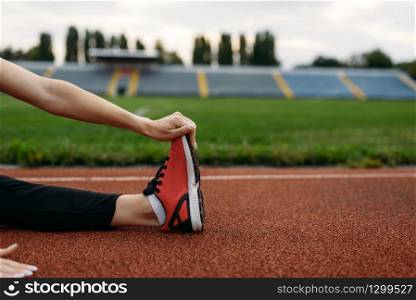Female runner in sportswear, workout on stadium. Woman doing stretching exercise before running on outdoor arena. Female runner in sportswear, workout on stadium
