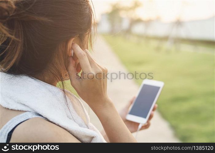Female runner jogging and using smartphone to listening music in the park, Outdoor workout