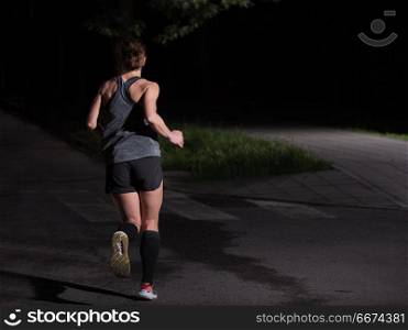female runner training for marathon. fit muscular female runner training for marathon running at night on beautiful road in nature.