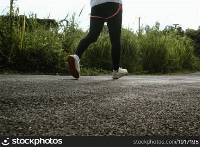 Female runners running on the road trail in morning training for marathon and fitness. Healthy lifestyle concept. Athlete running exercising outdoors. Close-up legs.