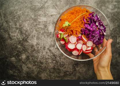female s hand holding fresh salad bowl grunge backdrop
