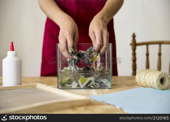 female s hand mixing paper water wooden desk