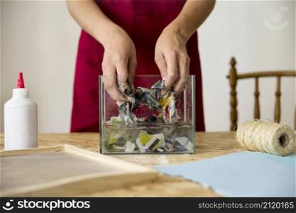 female s hand mixing paper water wooden desk