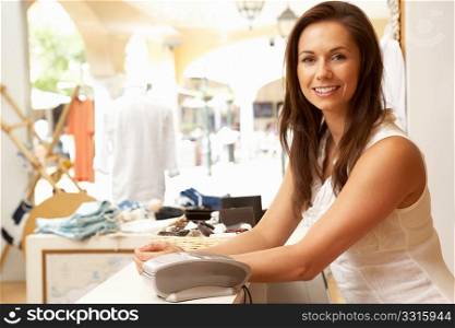 Female Sales Assistant At Checkout Of Clothing Store