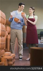 Female sales clerk showing pottery to a man