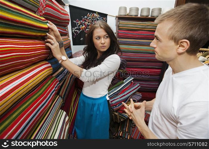 Female salesperson assisting man in textile store