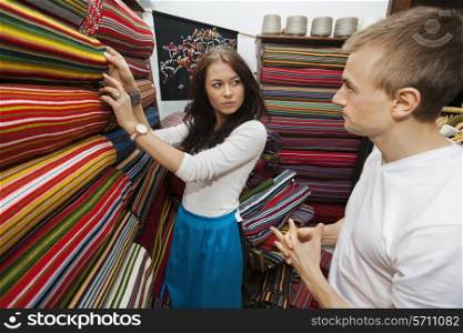 Female salesperson assisting man in textile store