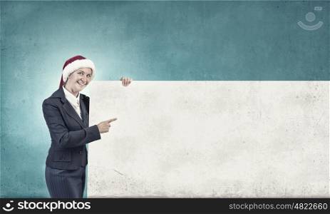 Female Santa with billboard. Woman in Santa hat pointing with finger at blank banner. Place for your text