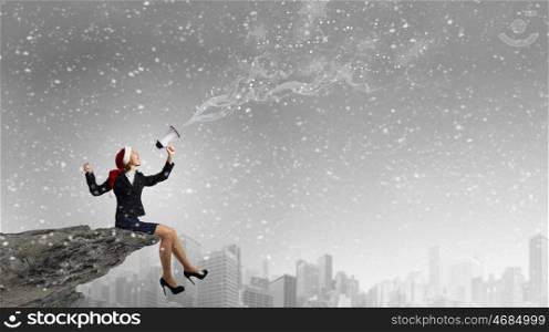 Female Santa with megaphone. Woman in suit and Santa hat shouting into megaphone