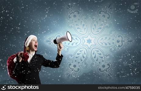 Female Santa with megaphone. Woman in suit and Santa hat shouting into megaphone
