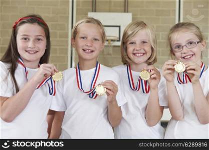Female School Sports Team In Gym With Medals