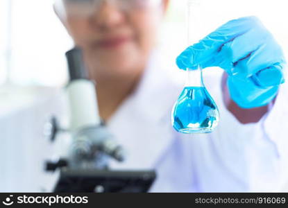 Female scientist hold and showing laboratory test tubes and solution with stethoscope. Science and Medical background. Scientist research and analysis biotechnology concept. Selective focus blue flask