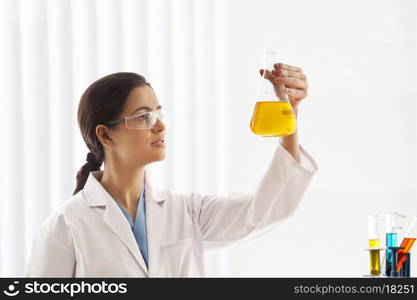 Female scientist holding flask of yellow liquid