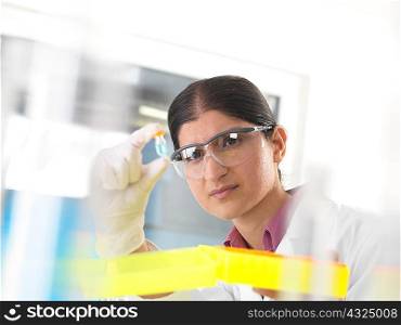 Female scientist holding up and examining chemical sample in lab