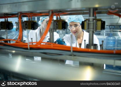 Female scientist in white coat and blue hat working in the control  machine of production line.