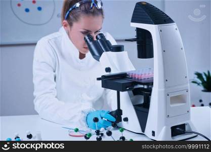 Female scientist looking through the microscope