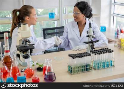 Female Scientist Shaking Hand With Colleague At Laboratory