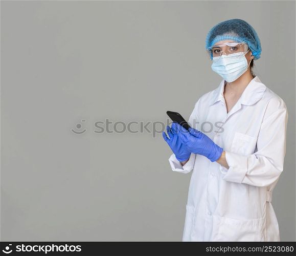 female scientist with safety glasses hair net holding smartphone