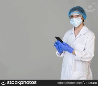 female scientist with safety glasses hair net holding smartphone