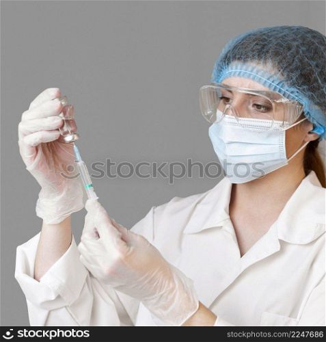 female scientist with safety glasses hair net holding syringe