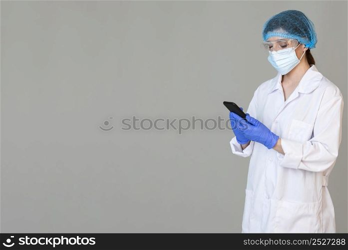 female scientist with safety glasses medical mask holding smartphone with copy space