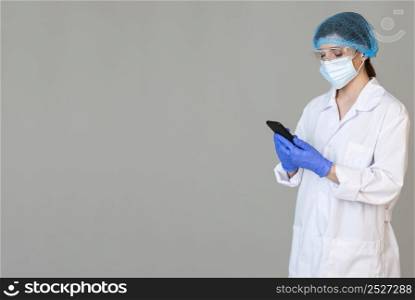 female scientist with safety glasses medical mask holding smartphone with copy space