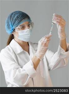 female scientist with safety glasses medical mask holding syringe