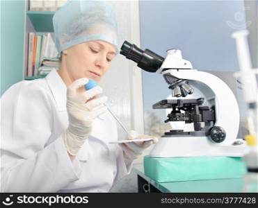 Female scientist working at the laboratory. White uniform and gloves. Focus on the face and hands.