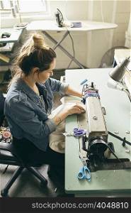 Female seamstress using sewing machine in fashion studio