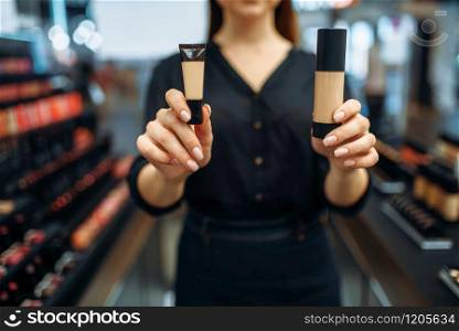 Female seller shows cosmetics in the makeup shop. Woman in beauty store, make-up