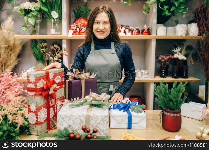 Female seller with gift boxes in festive wrapping paper with ribbons, handmade decoration. Presents packing service, diy decor