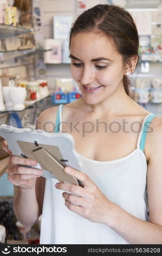 Female Shopper Looking At Picture Frame In Gift Shop