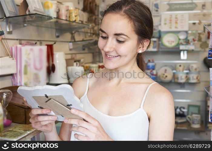 Female Shopper Looking At Picture Frame In Gift Shop