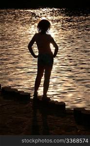 Female silhouette near water on sunset