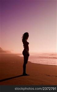Female silhouette of a beautiful young girl on the beach at the sunset