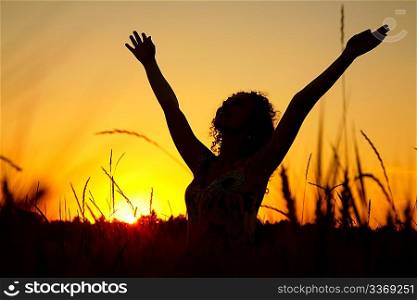 Female silhouette on sunset on wheaten field