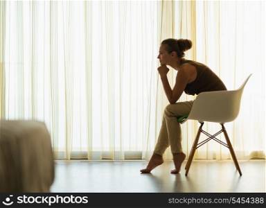 Female sitting near window in thoughtful pose and looking on copy space