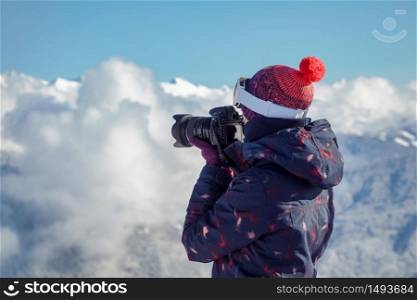 Female skier photographs in mountains, beautiful sunny day