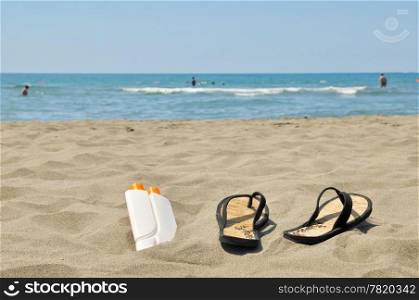 Female slippers and sun cream on beach stock photo