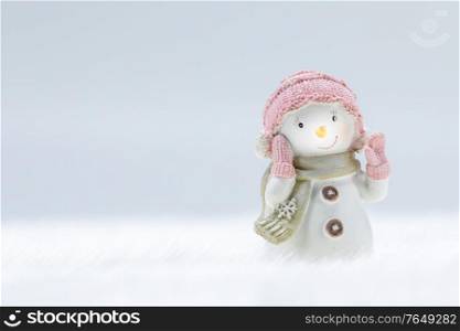 Female Snowman toy on frozen snow light winter background with copy space. Snowman toy on winter background