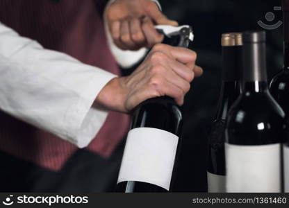 Female sommelier opening wine bottle with corkscrew