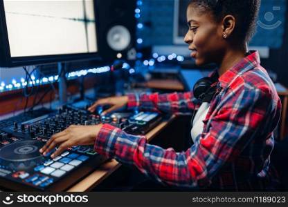 Female sound engineer working at the remote control panel in the recording studio. Musician at the mixer, professional audio mixing