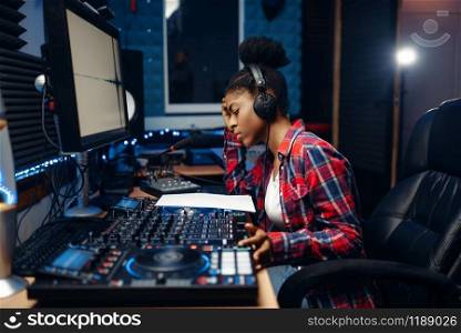 Female sound operator working at the remote control panel in audio recording studio. Musician at the mixer, professional music mixing. Female sound operator in audio recording studio
