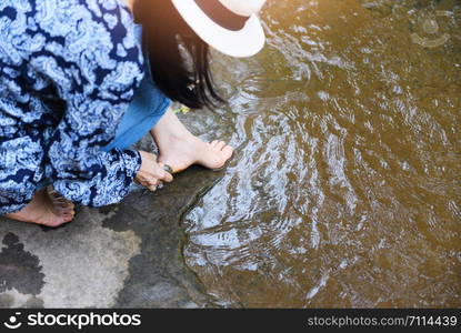 Female spa feet cleaning with stone on the nature river stream / woman having her feet scrubbed , Spa foot massage