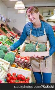 female staff holding broccoli in organic section