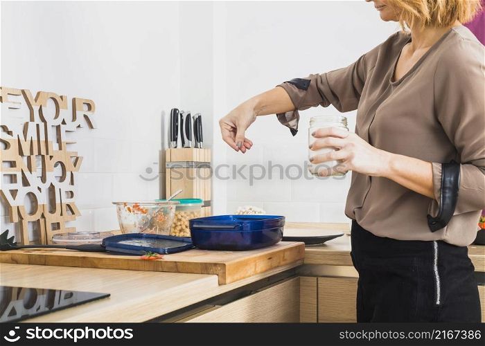 female standing kitchen salting food