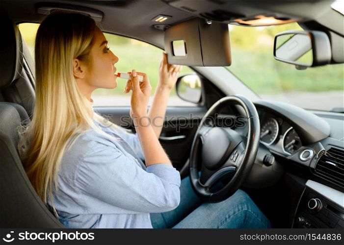 Female student applies makeup in car, lesson in driving school. Man teaching lady to drive vehicle. Driver&rsquo;s license education. Female student applies makeup, driving school