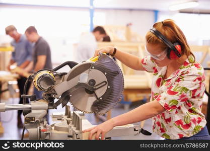 Female Student In Carpentry Class Using Circular Saw