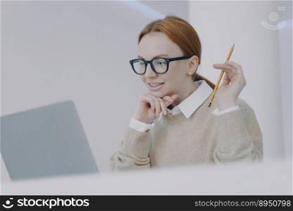 Female student is reading on PC. Smiling girl is browsing information and doing research. Adviser or manager at workplace in modern office. Successful attractive girl is studying.. Female student is reading on PC. Smiling girl is browsing information and doing research.